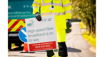 Worker holding a sign with "High speed broadband is on the way" wrote on it